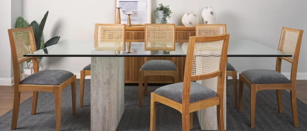 Mesa de comedor moderna con cubierta de vidrio y sillas de madera, ilustrando la elección de mobiliario para el hogar.